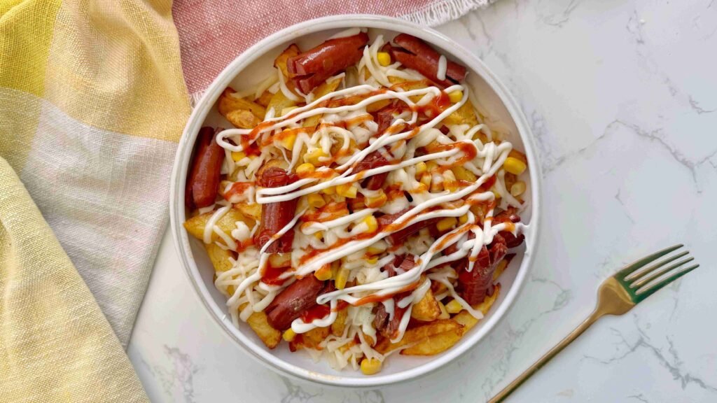 Salchipapas served in a bowl with sauce toppings