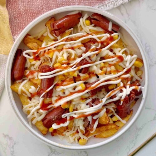 Salchipapas served in a bowl with sauce toppings