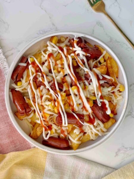 Salchipapas served in a bowl with sauce toppings