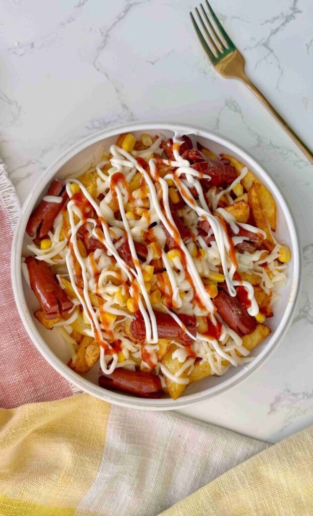 Salchipapas served in a bowl with sauce toppings