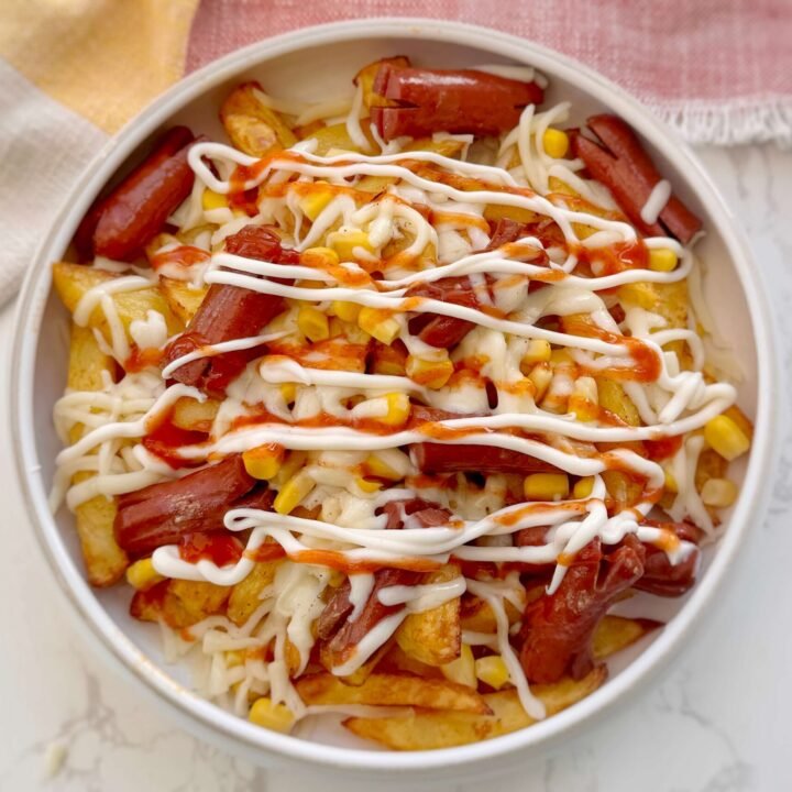 Salchipapas served in a bowl with sauce toppings