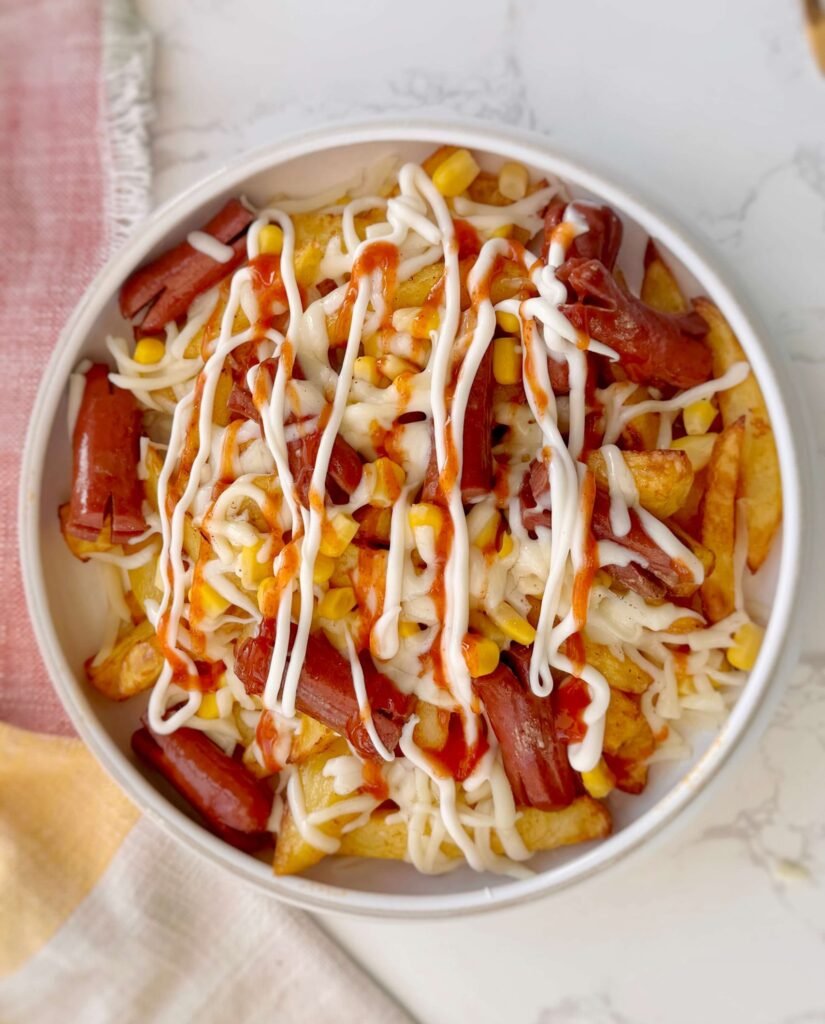Salchipapas served in a bowl with sauce toppings