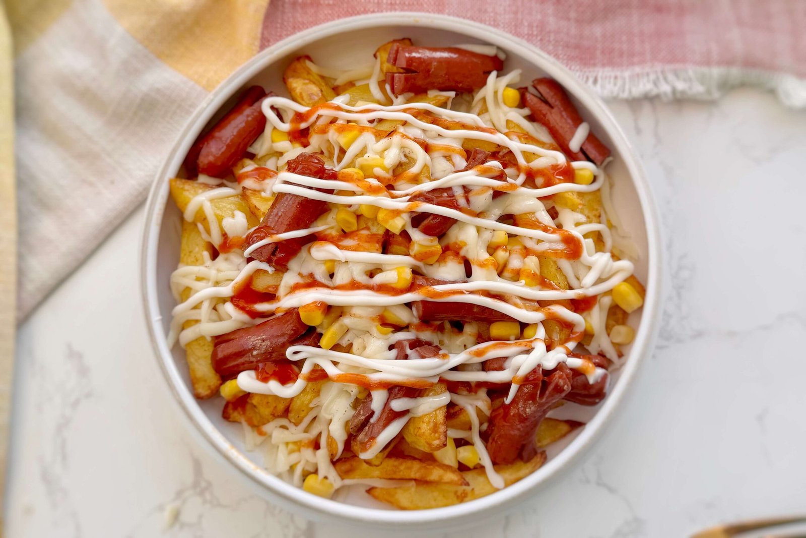Salchipapas served in a bowl with sauce toppings