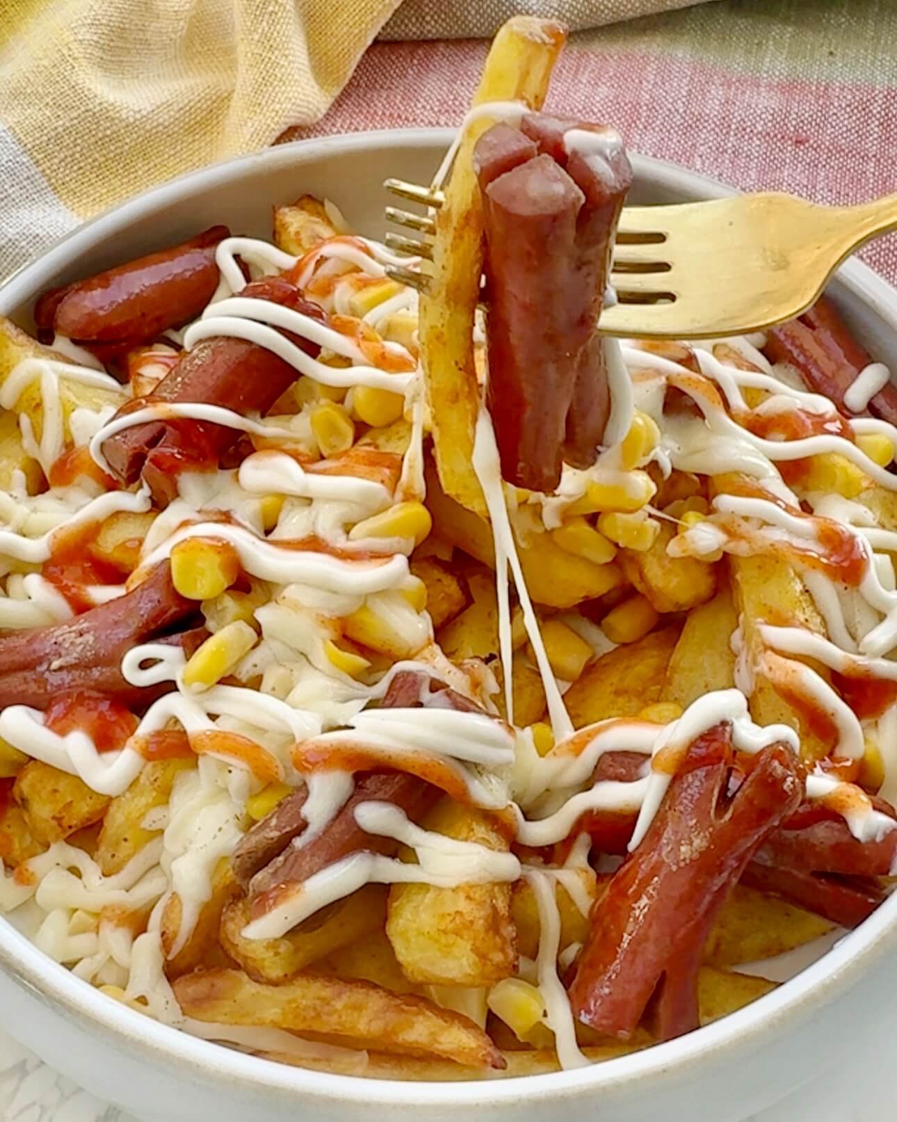Salchipapas served in a bowl with sauce toppings