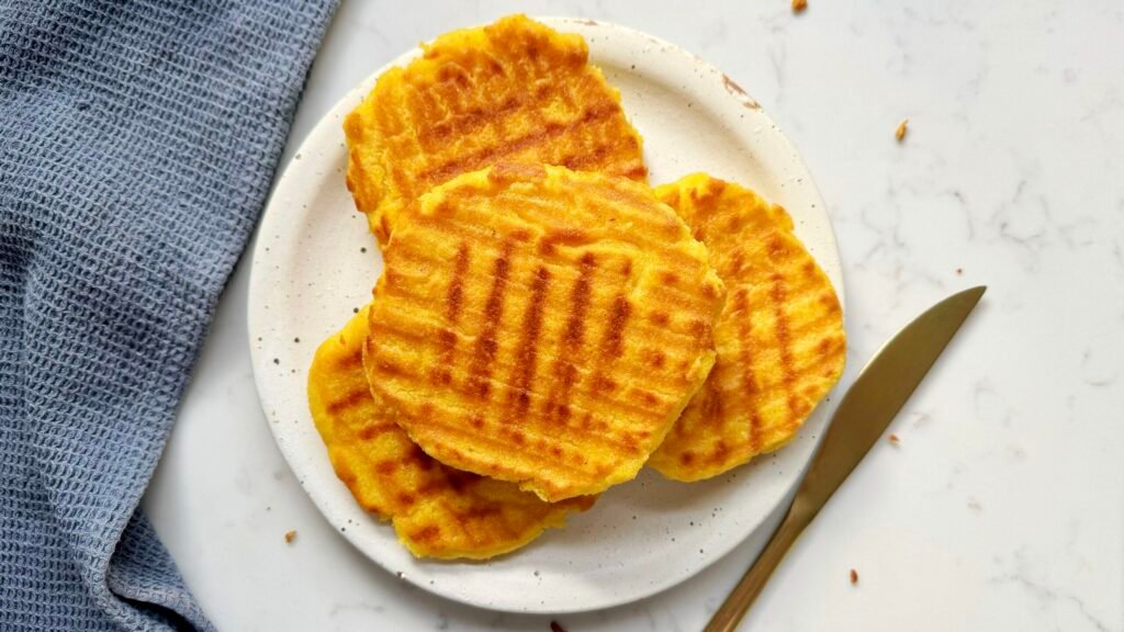 A plate of food showing 3 Arepa de Choclo