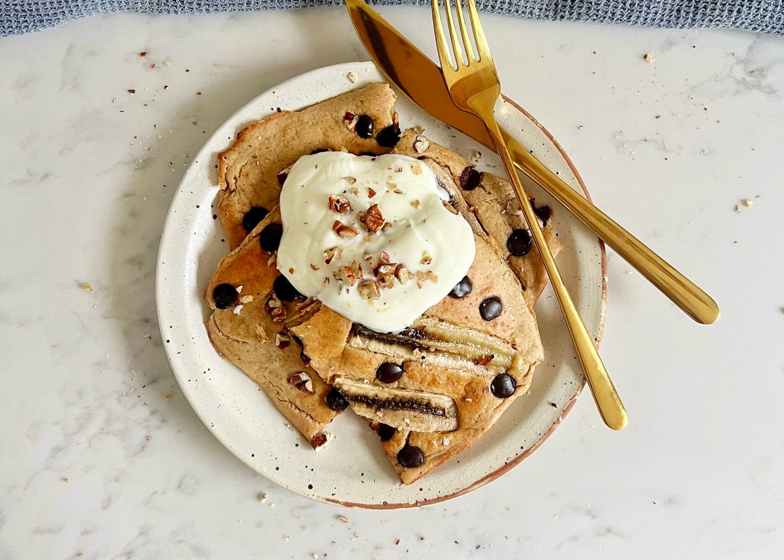 "Deliciosos Banana Bread Sheet Pan Pancakes horneados en una bandeja, cortados en porciones y decorados con rodajas de plátano y chispas de chocolate