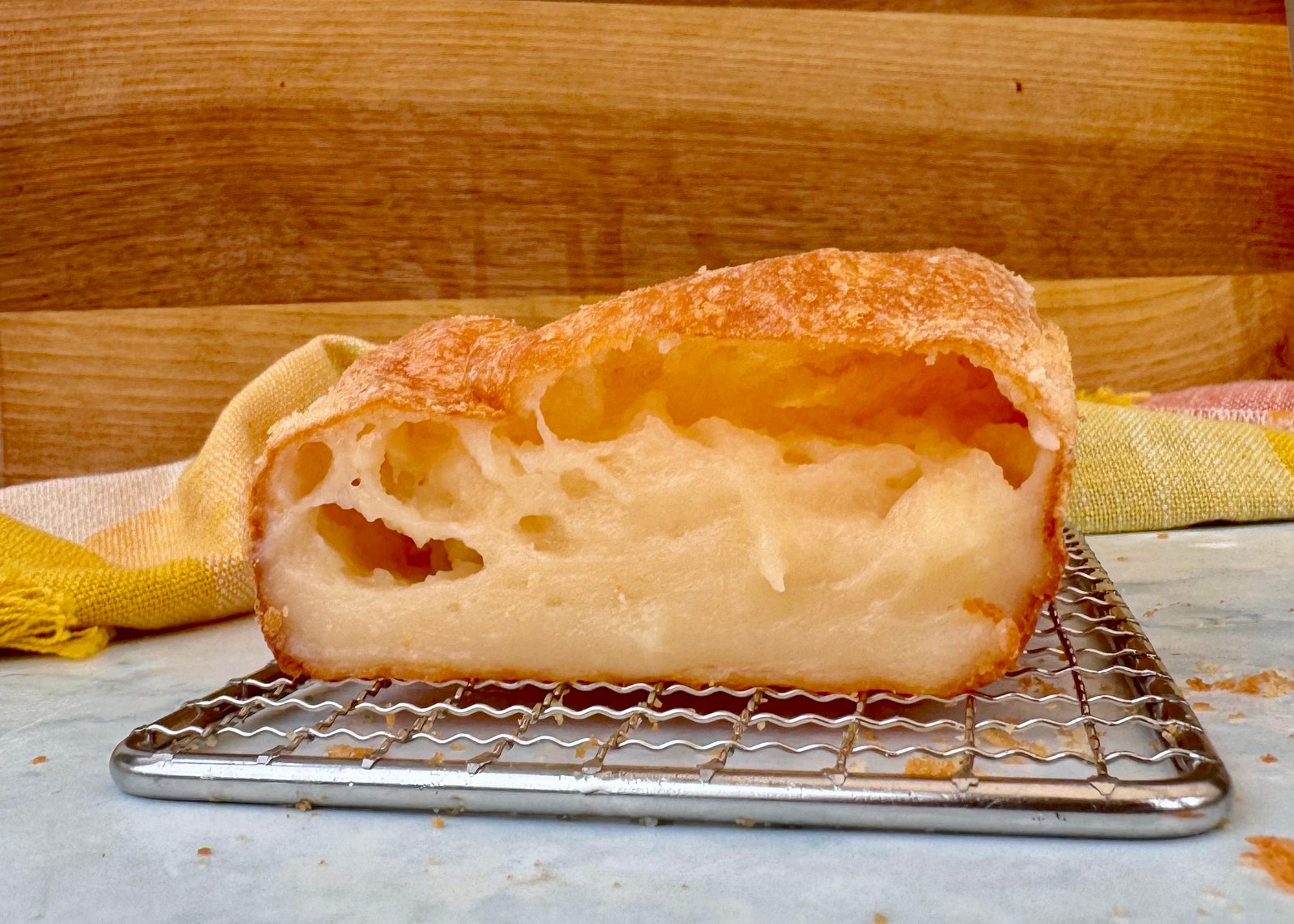 Golden-brown Cheese Bread Cake with a soft, cheesy interior, freshly baked and sliced on a wooden board