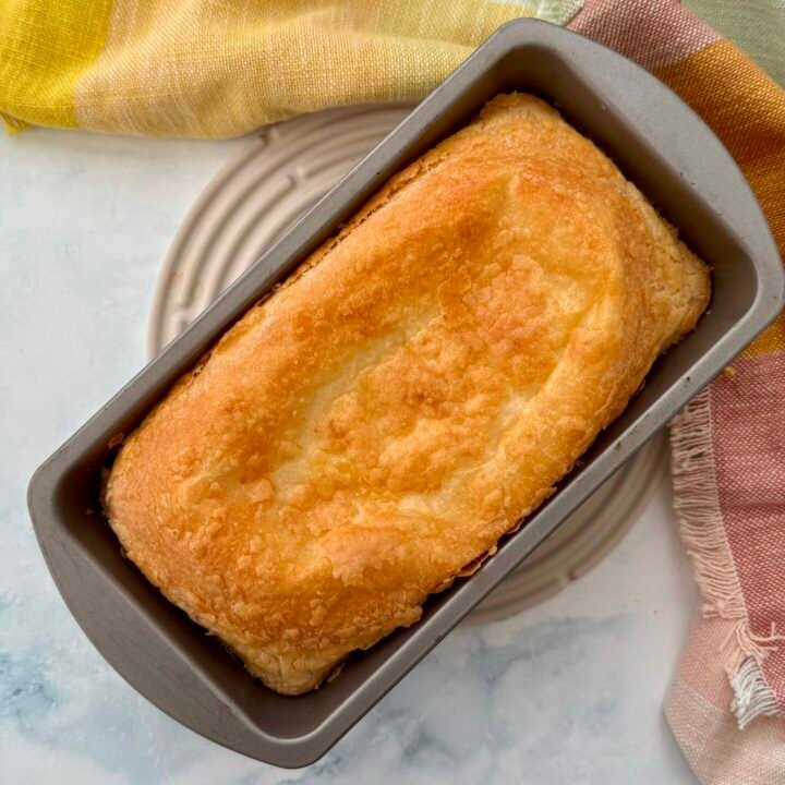 Golden-brown Cheese Bread Cake with a soft, cheesy interior, freshly baked and sliced on a wooden board