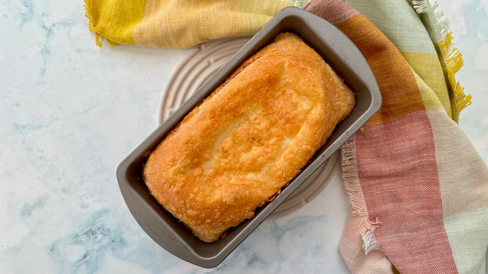 Golden-brown Cheese Bread Cake with a soft, cheesy interior, freshly baked and sliced on a wooden board
