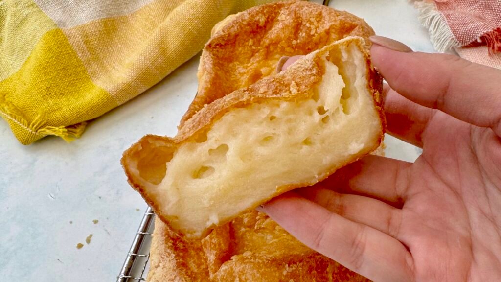 Golden-brown Cheese Bread Cake with a soft, cheesy interior, freshly baked and sliced on a wooden board