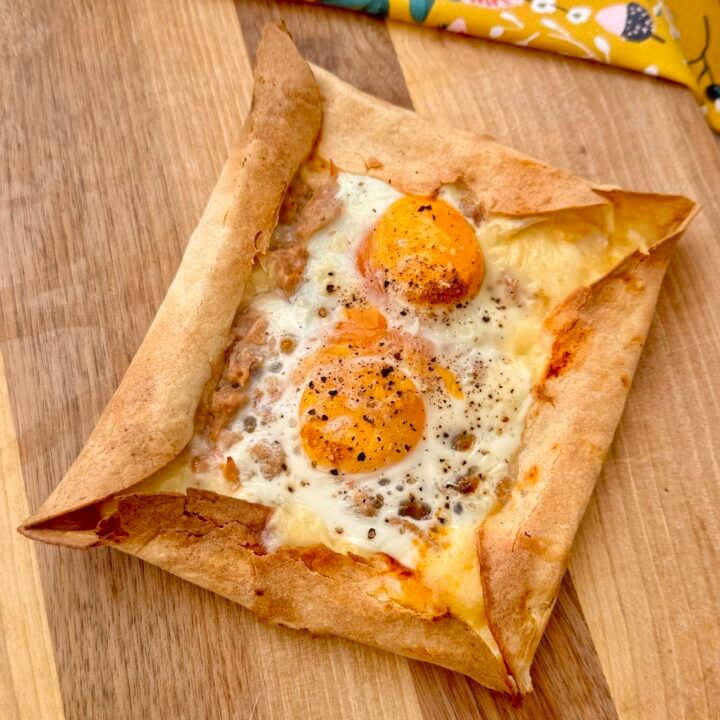 A crispy cheese-crust egg pizza with golden edges, topped with runny eggs, tuna, and rich Arrabbiata sauce, served fresh from the air fryer.