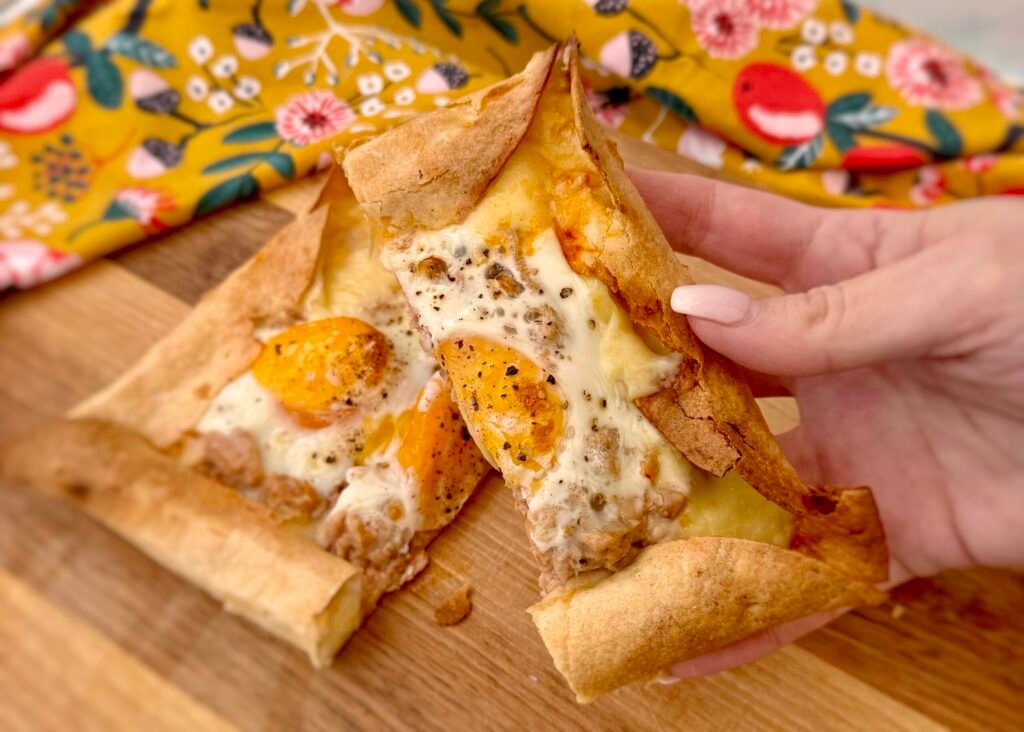 A crispy cheese-crust egg pizza with golden edges, topped with runny eggs, tuna, and rich Arrabbiata sauce, served fresh from the air fryer.