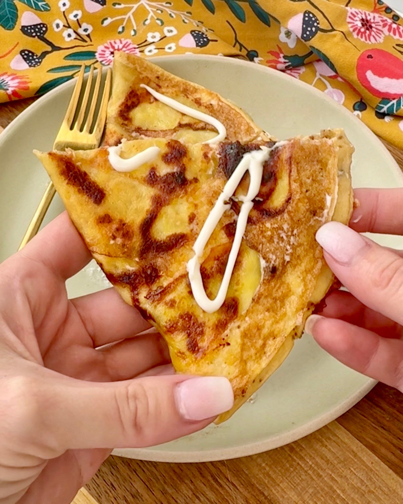  A golden, crispy Cheesy Potato Omelette in a skillet, featuring thinly sliced potatoes, melted cheese, and fluffy eggs, garnished with fresh herbs.