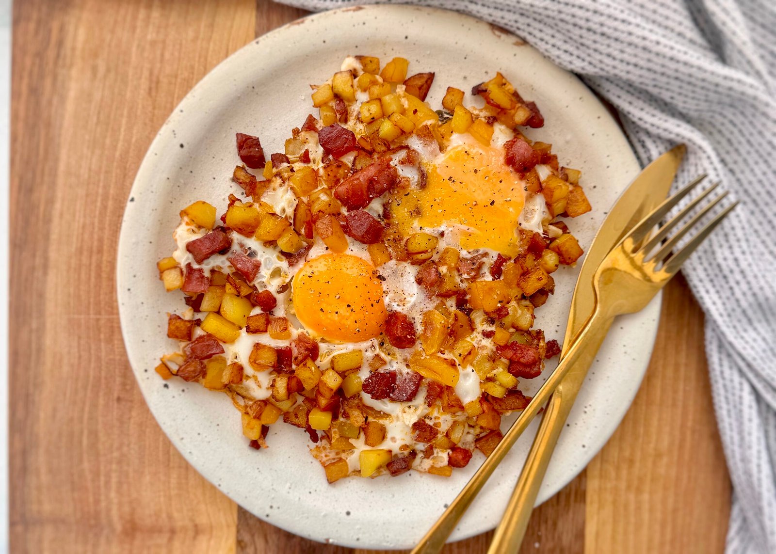 A hearty and flavorful Chorizo Egg Hash served in a skillet. Crispy golden-brown potatoes, smoky chorizo, and perfectly cooked eggs with runny yolks are garnished with paprika and fresh herbs. The dish is vibrant with yellow bell peppers and caramelized onions, making it a delicious and satisfying one-pan meal.