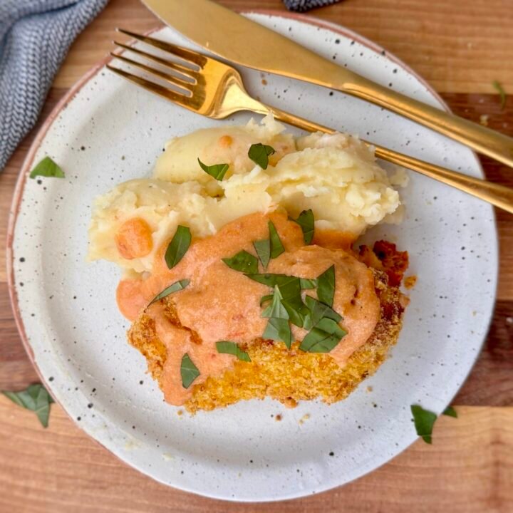 Golden, crispy Marry Me Chicken Kiev sliced open to reveal a rich sun-dried tomato and Parmesan filling, served with creamy mashed potatoes and a drizzle of cottage cheese sauce, garnished with fresh basil.