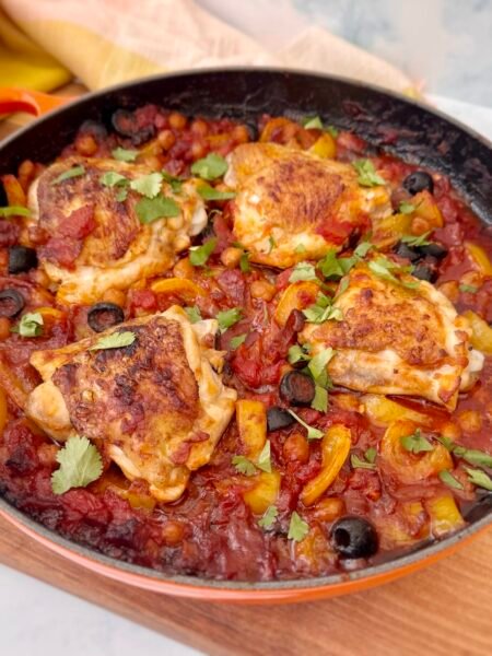 A rustic, Spanish-inspired one-pot chicken dish featuring golden-browned chicken thighs, smoky chorizo, tender chickpeas, sweet yellow peppers, and briny black olives, all simmered in a rich tomato sauce. Garnished with fresh parsley and served with lemon wedges, this hearty Mediterranean meal is both flavorful and nourishing. Perfect for an easy weeknight dinner or a cozy gathering.