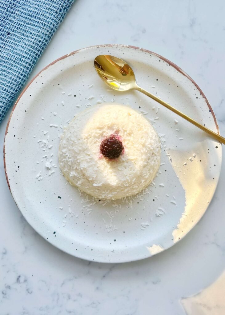 Flourless coconut yogurt cake topped with fresh blackberries, served on a rustic plate.