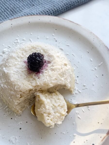 Flourless coconut yogurt cake topped with fresh blackberries, served on a rustic plate.