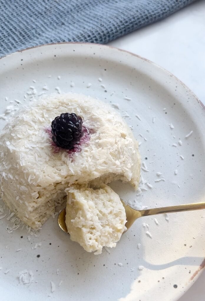 Flourless coconut yogurt cake topped with fresh blackberries, served on a rustic plate.