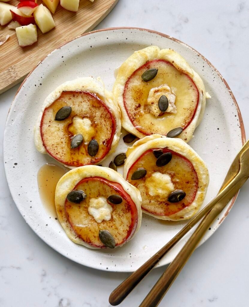 Spiced apple pancakes with caramelised apple rings and pumpkin seeds on a plate