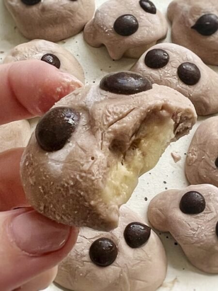 Chocolate banana protein bites topped with yogurt and chocolate chips on a parchment-lined tray