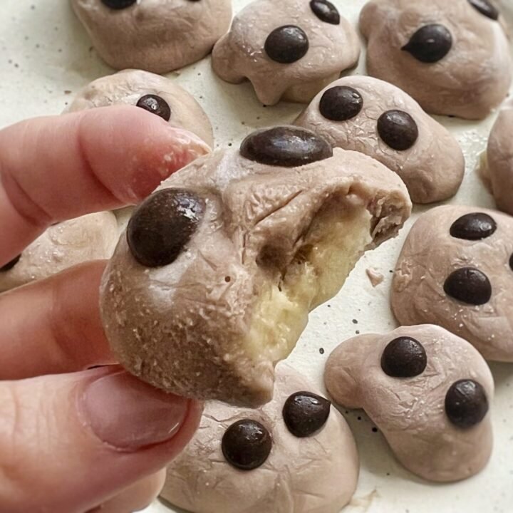Chocolate banana protein bites topped with yogurt and chocolate chips on a parchment-lined tray