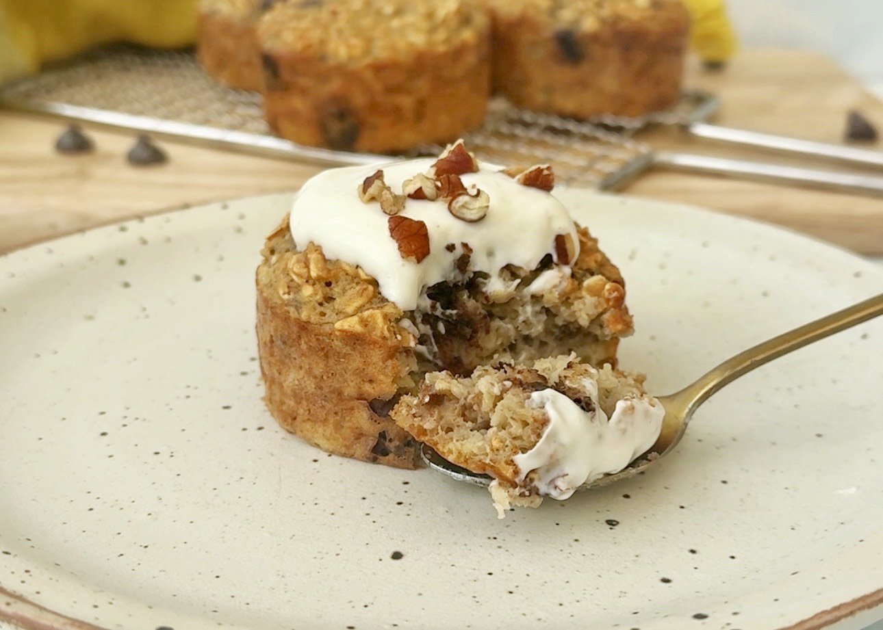 Freshly baked banana bread breakfast muffins topped with Skyr and chopped nuts, served on a rustic wooden board.