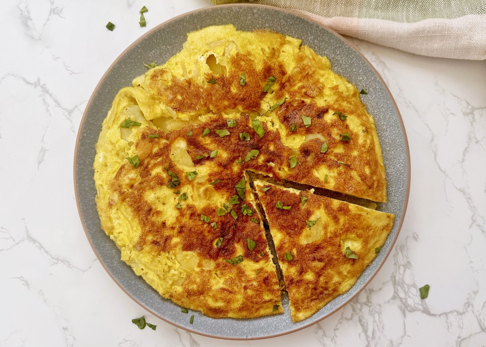 a plate of omelette with a slice cut out, spanish tortilla