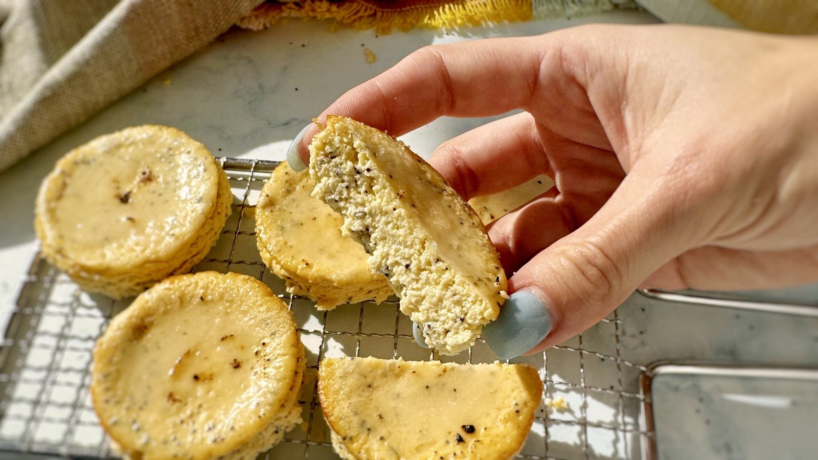 Mini Lemon and Poppyseed Cottage Cheesecakes served in paper liners, topped with lemon zest and fresh berries on a white plate