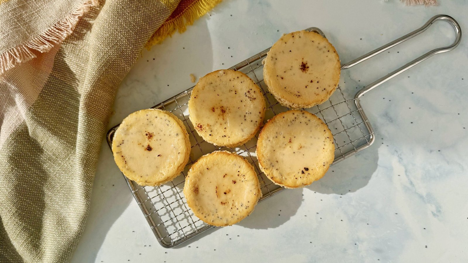 Mini Lemon and Poppyseed Cottage Cheesecakes served in paper liners, topped with lemon zest and fresh berries on a white plate