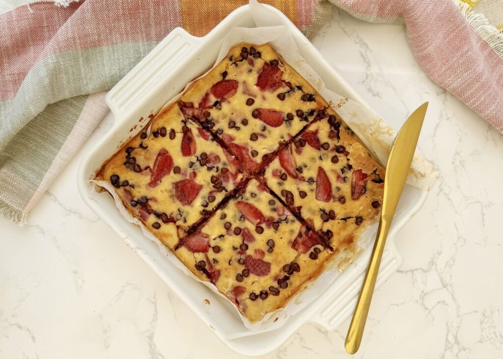 aked strawberry and dark chocolate pancakes in a tray, sliced and drizzled with pistachio butter.