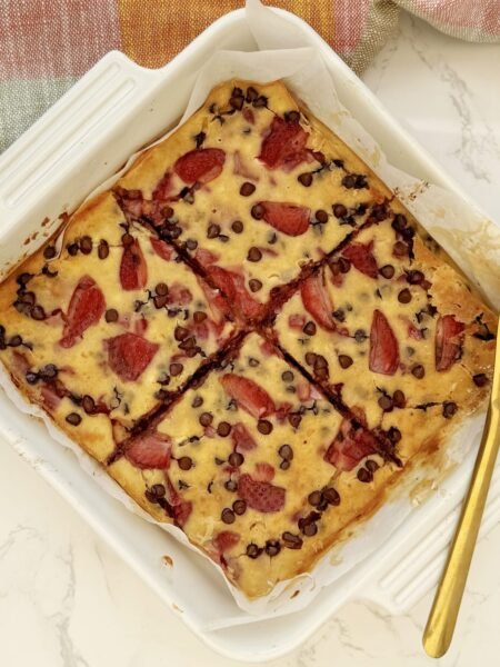 aked strawberry and dark chocolate pancakes in a tray, sliced and drizzled with pistachio butter.