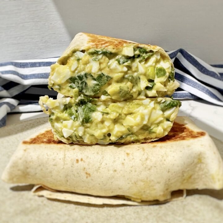 Toasted chopped egg salad wrap filled with avocado, Skyr, spinach and mustard on a wooden board