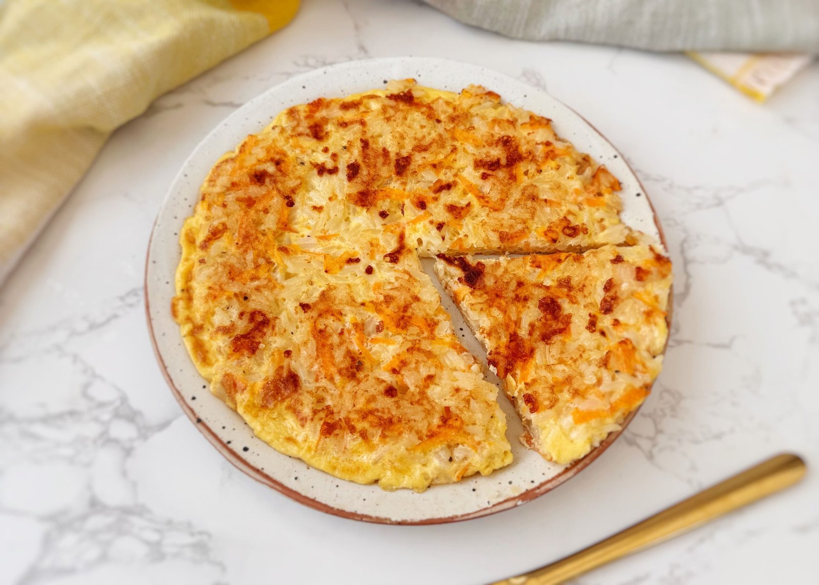 A golden-brown Crispy Rice and Carrot Pie sliced into wedges on a plate, with visible flecks of carrot and melted cheese.