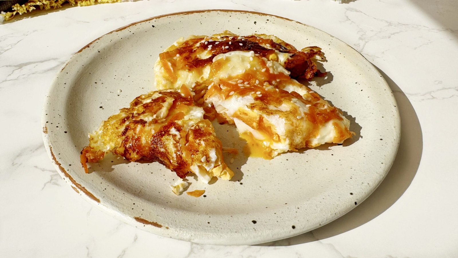 Hot Honey Crispy Carrot Eggs in a non-stick pan with runny yolks, golden mozzarella crust, grated carrots, and sesame seeds – a spicy, high-protein vegetarian breakfast perfect for quick UK brunch recipes.