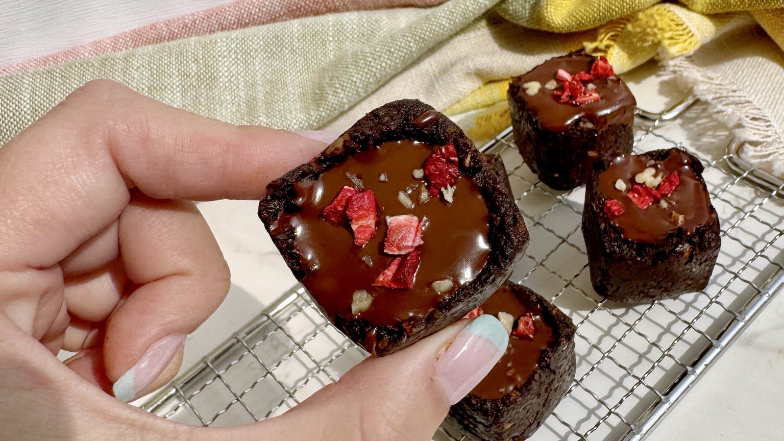 A tray of Raw Date Brownie Cups with Berry Jam, showing rich chocolatey cups filled with vibrant berry jam and topped with melted dark chocolate.