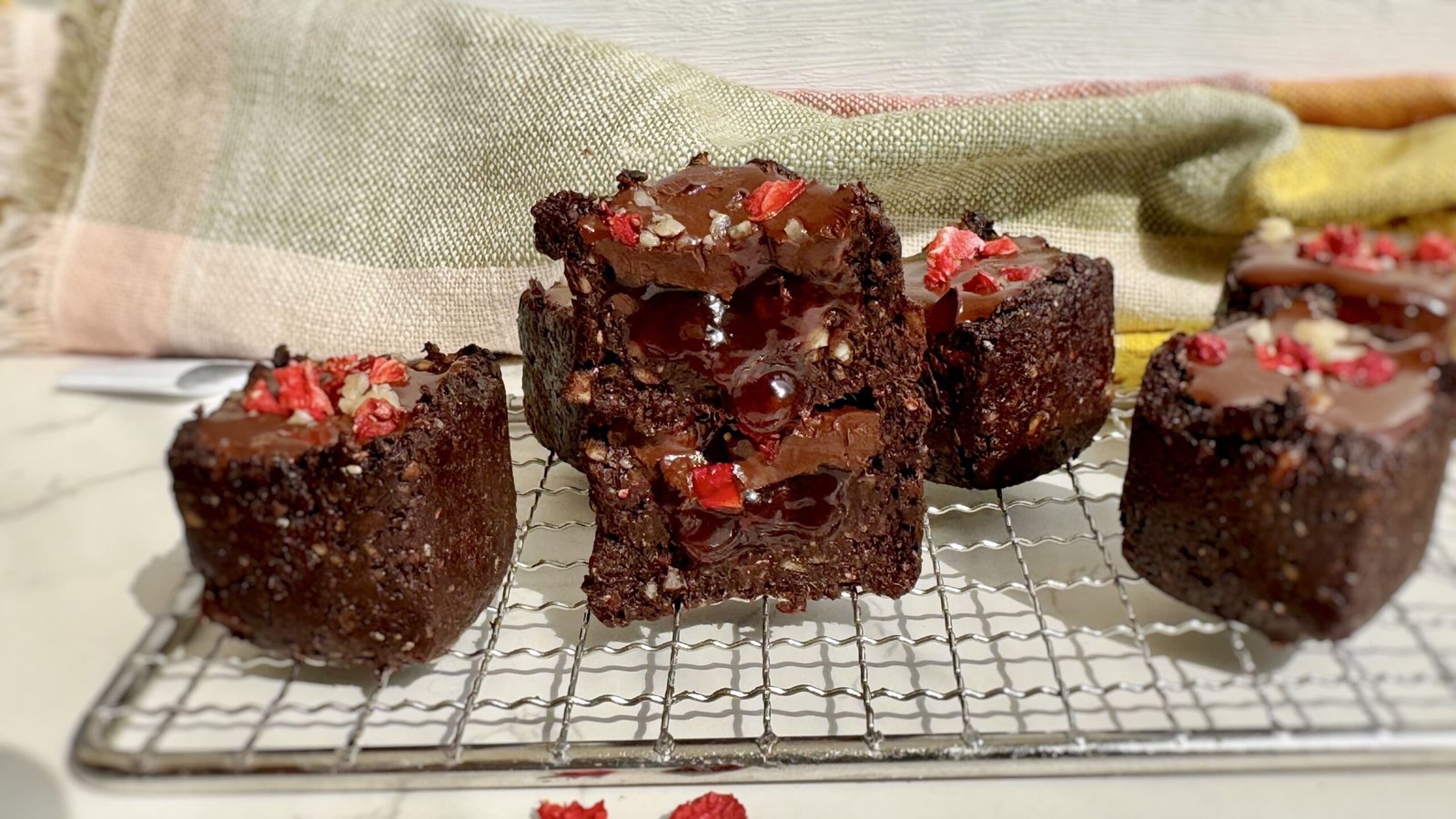 A tray of Raw Date Brownie Cups with Berry Jam, showing rich chocolatey cups filled with vibrant berry jam and topped with melted dark chocolate.