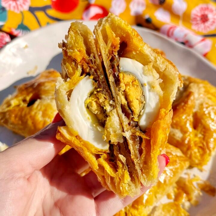 Golden, flaky Kerala egg puffs with spiced onion filling and halved boiled eggs, served on parchment with a side of chutney.