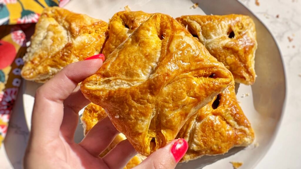 Golden, flaky Kerala egg puffs with spiced onion filling and halved boiled eggs, served on parchment with a side of chutney.