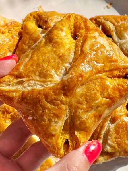 Golden, flaky Kerala egg puffs with spiced onion filling and halved boiled eggs, served on parchment with a side of chutney.