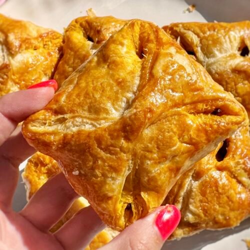Golden, flaky Kerala egg puffs with spiced onion filling and halved boiled eggs, served on parchment with a side of chutney.
