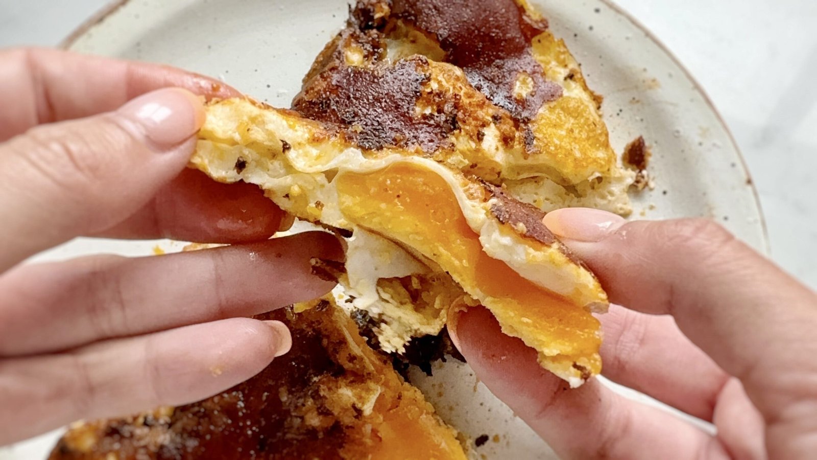 Close-up of crispy mozzarella and red pesto eggs in a frying pan, with golden cheese edges, vibrant red pesto base, and perfectly cooked sunny-side-up eggs. Preguntar a ChatGPT