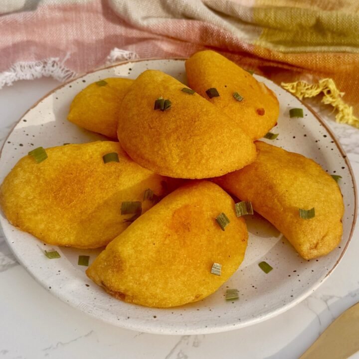 Golden, air-fried Egg Breakfast Empanadas filled with scrambled eggs, ham, and cheese on a serving plate.