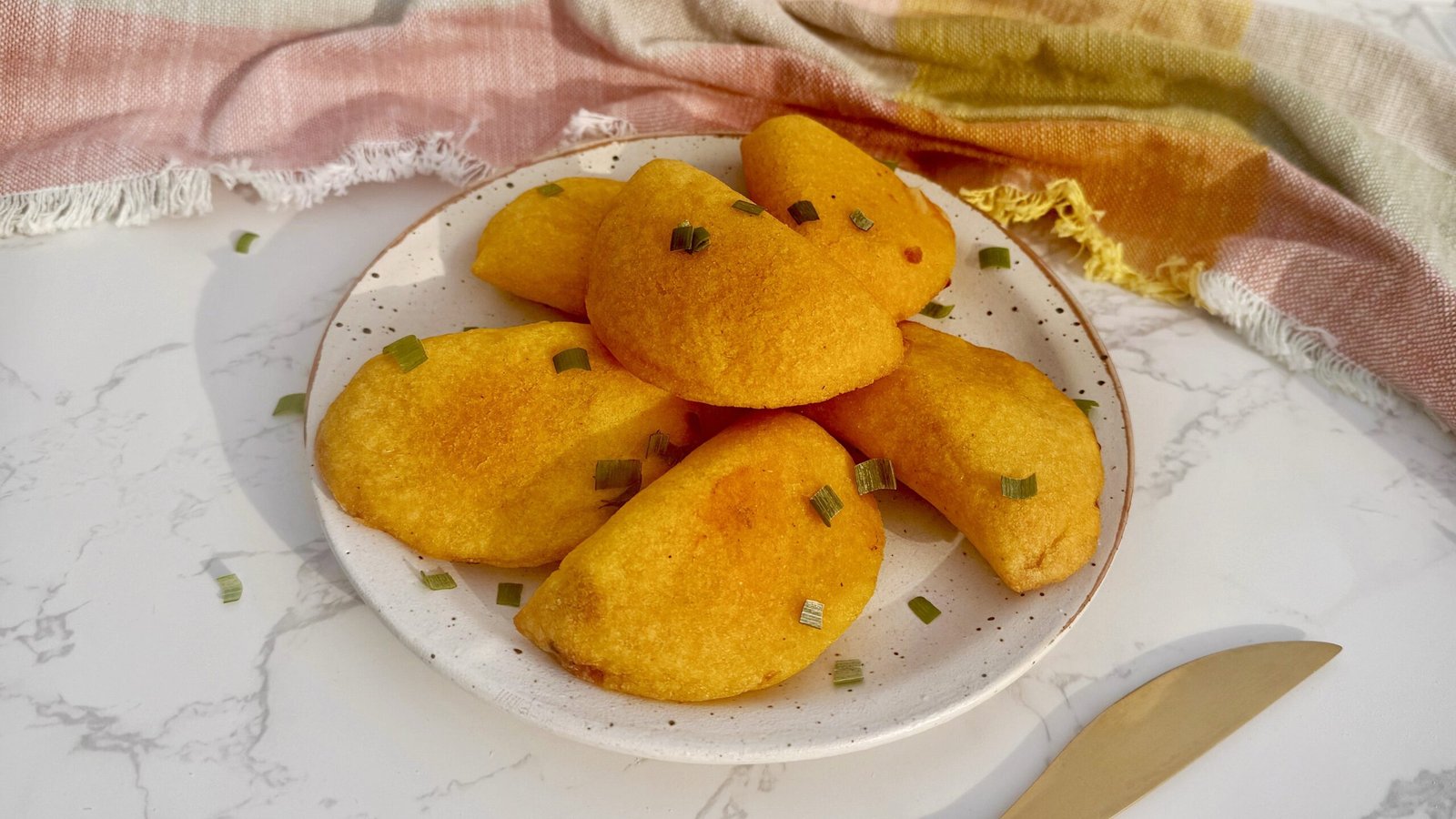 Golden, air-fried Egg Breakfast Empanadas filled with scrambled eggs, ham, and cheese on a serving plate.