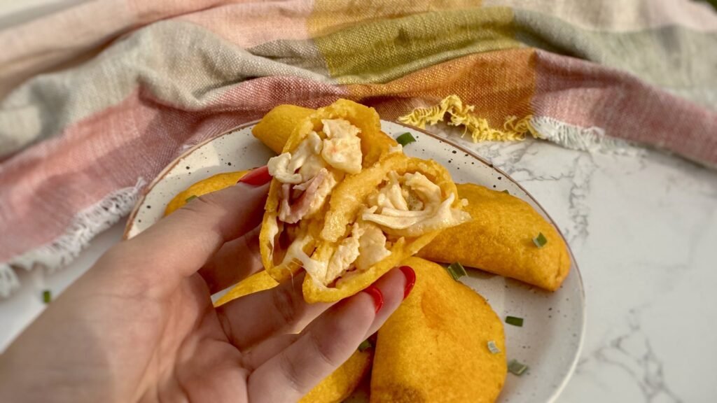 Golden, air-fried Egg Breakfast Empanadas filled with scrambled eggs, ham, and cheese on a serving plate.