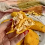 Golden, air-fried Egg Breakfast Empanadas filled with scrambled eggs, ham, and cheese on a serving plate.