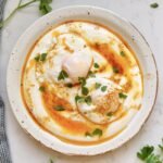 Turkish Eggs (Çılbır) served with poached eggs on creamy yoghurt, drizzled with spiced butter and herbs.