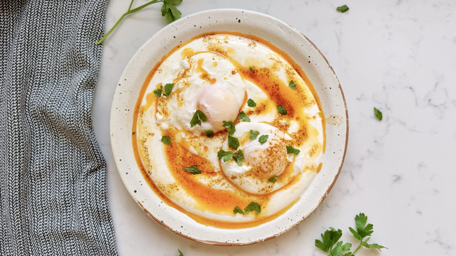 Turkish Eggs (Çılbır) served with poached eggs on creamy yoghurt, drizzled with spiced butter and herbs.
