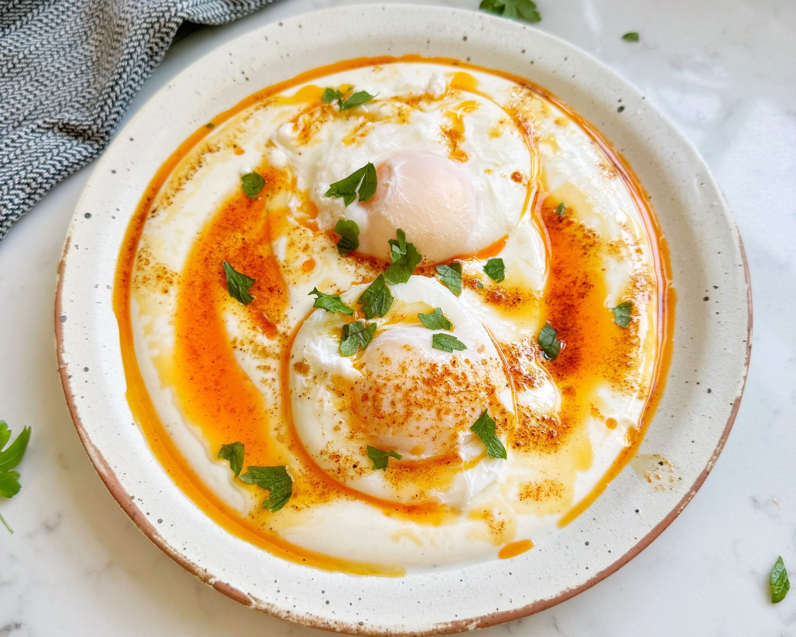 Turkish Eggs (Çılbır) served with poached eggs on creamy yoghurt, drizzled with spiced butter and herbs.