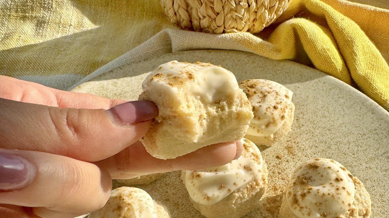 Pumpkin spice cheesecake protein balls coated in cream cheese icing on parchment paper